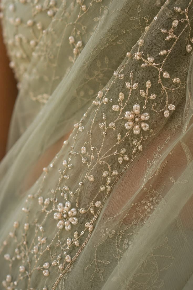 Macro detail of pearl hand-embroidery on sage-green tulle